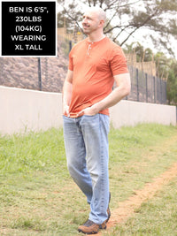 Thumbnail for A head to toe shot of a tall skinny guy wearing a tall brown henley shirt.