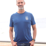 An upper body shot of a tall slim guy in an L tall graphic t-shirt with a lake design, hands in pockets.