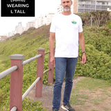 A head to toe shot of a tall slim guy in an L tall graphic t-shirt with a landscape design.