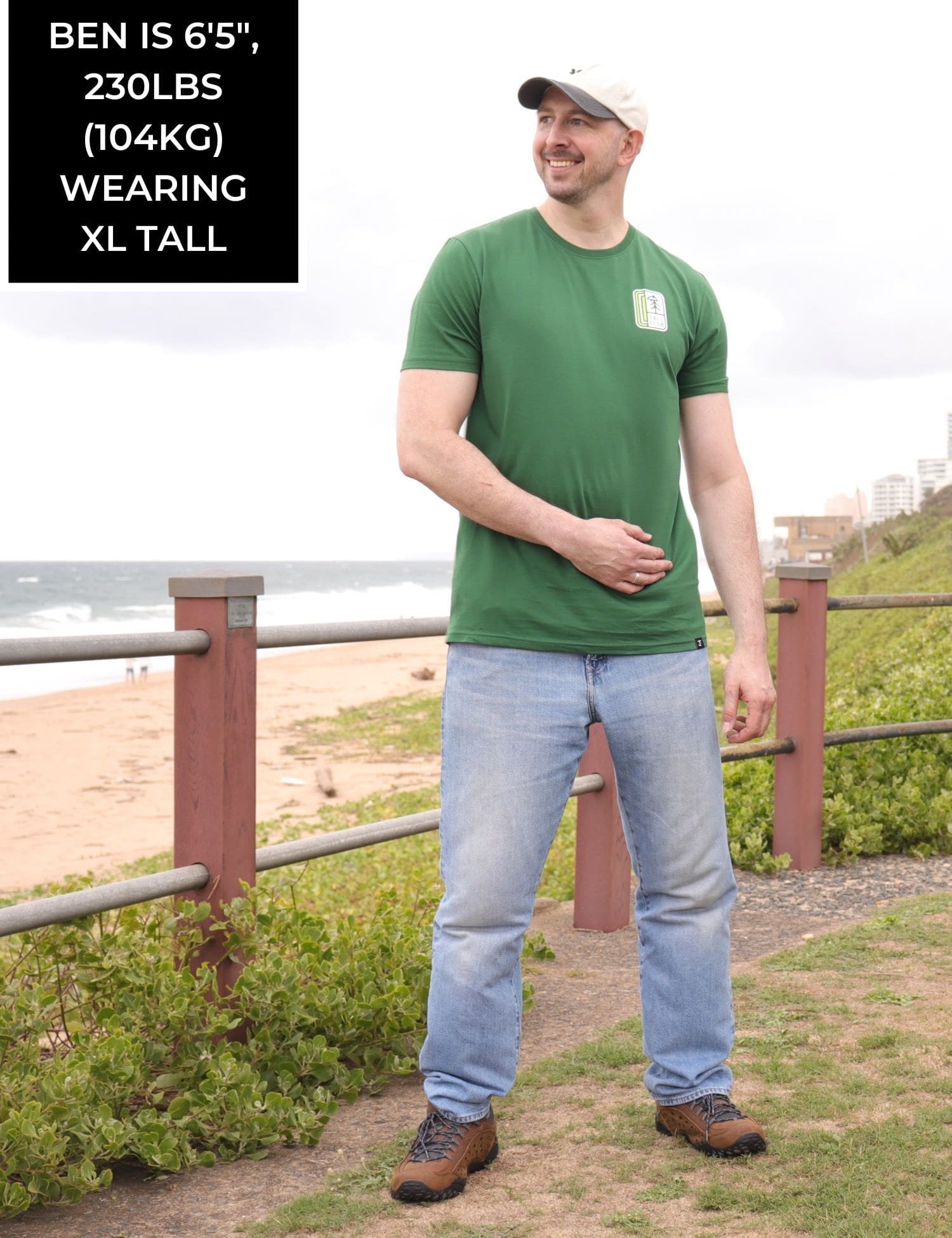 A head to toe shot of a tall slim guy in an XL tall graphic t-shirt with a tall club design.