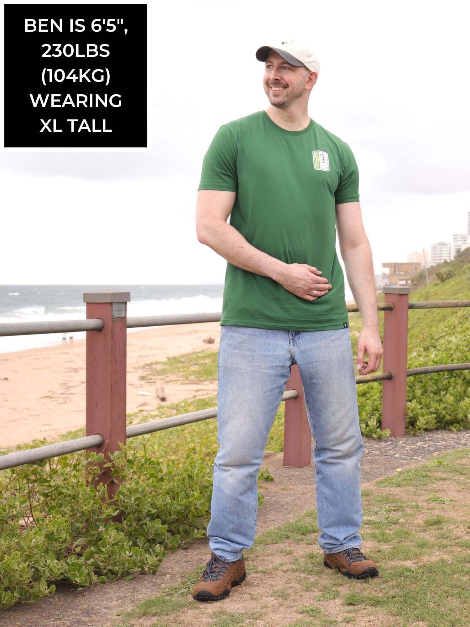 A head to toe shot of a tall slim guy in an XL tall graphic t-shirt with a tall club design.
