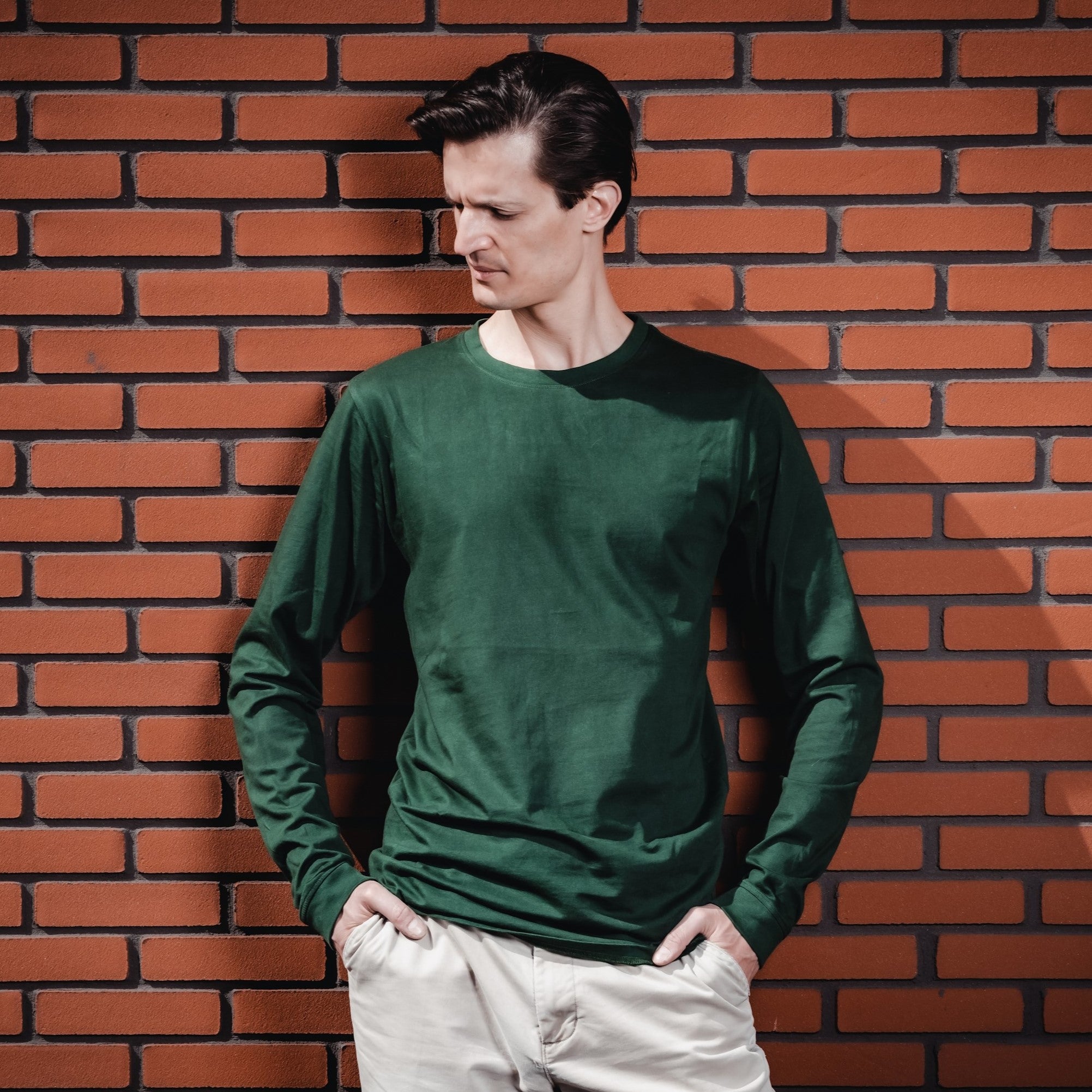 A tall slim guy wearing a dark green tall long sleeve t-shirt.