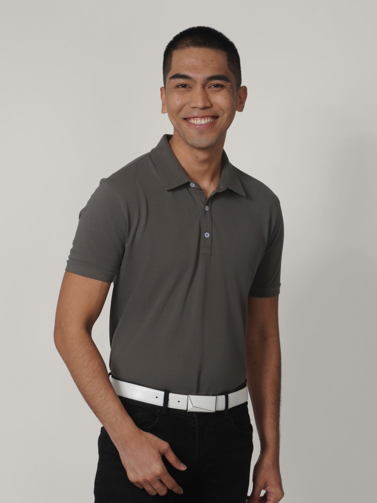A tall skinny guy smiling and wearing a grey medium tall polo shirt.