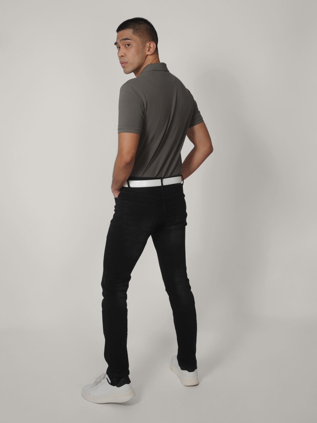 A shot from behind of a tall skinny guy wearing a tall grey pique polo shirt.