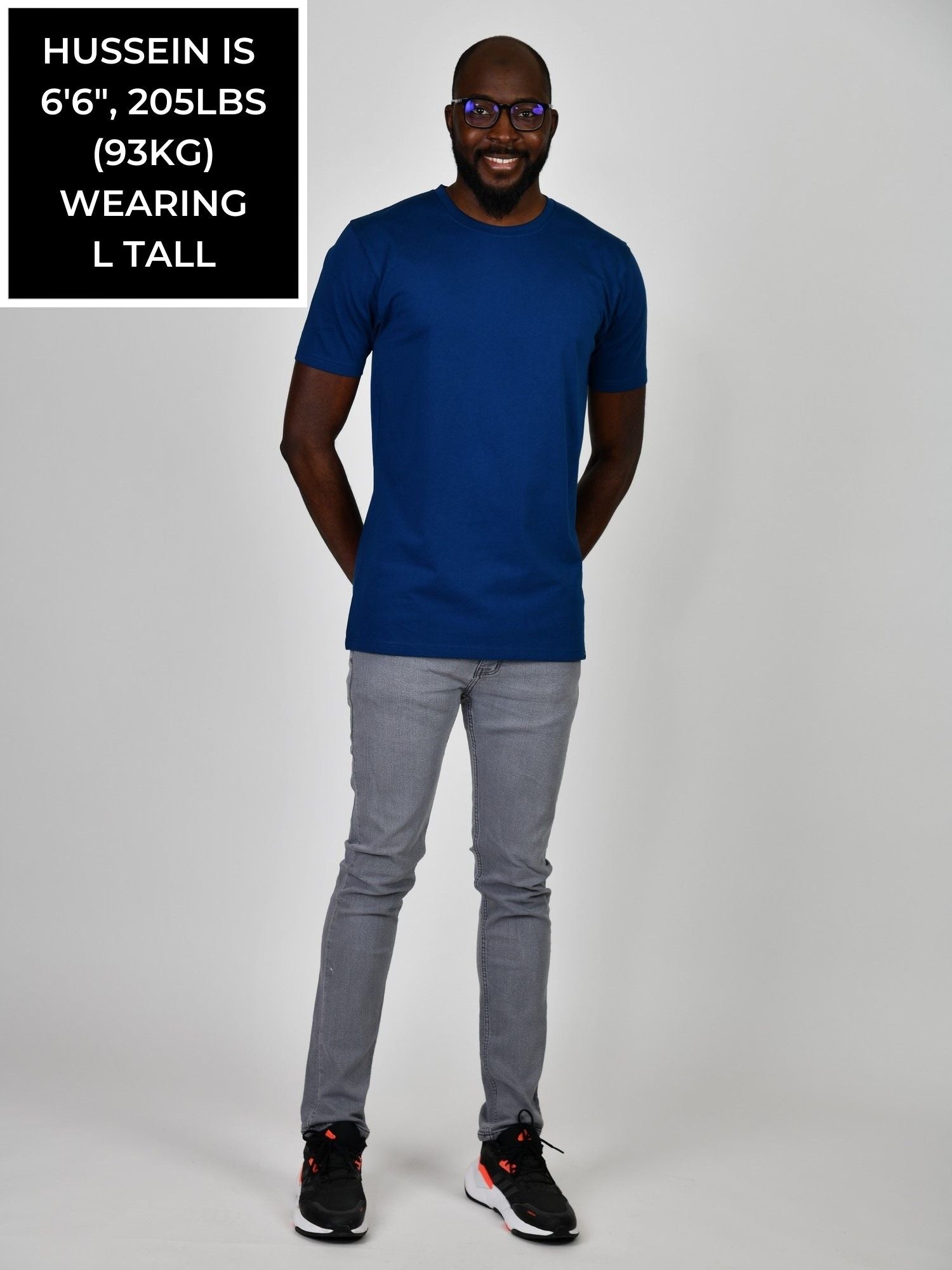 A head to toe shot of a tall athletic guy wearing a navy large tall t-shirt.