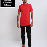 A head to toe shot of a tall skinny guy in the studio wearing a red small tall slim t-shirt.