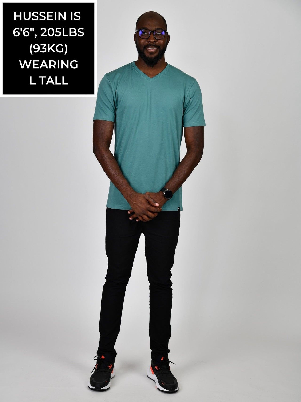 A head to toe shot of a tall and slim guy in the studio wearing a teal L tall slim v-neck t-shirt.