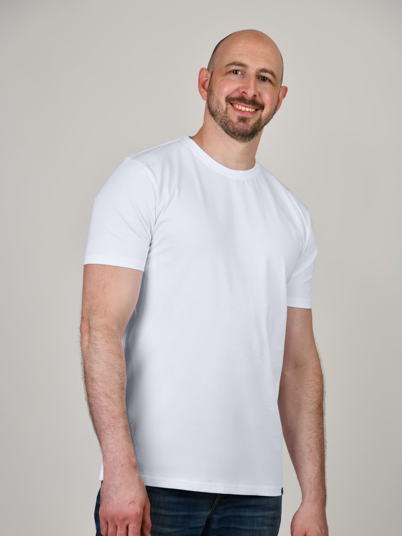 A tall and slim guy in the studio wearing a white XL tall slim t-shirt.