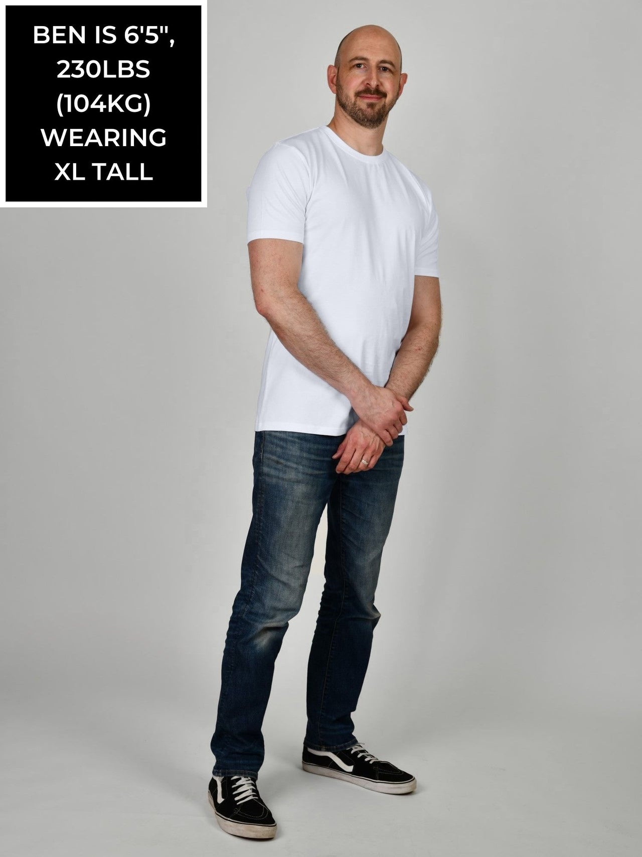 A head to toe shot of a tall and slim guy in the studio wearing a white XL tall slim t-shirt.