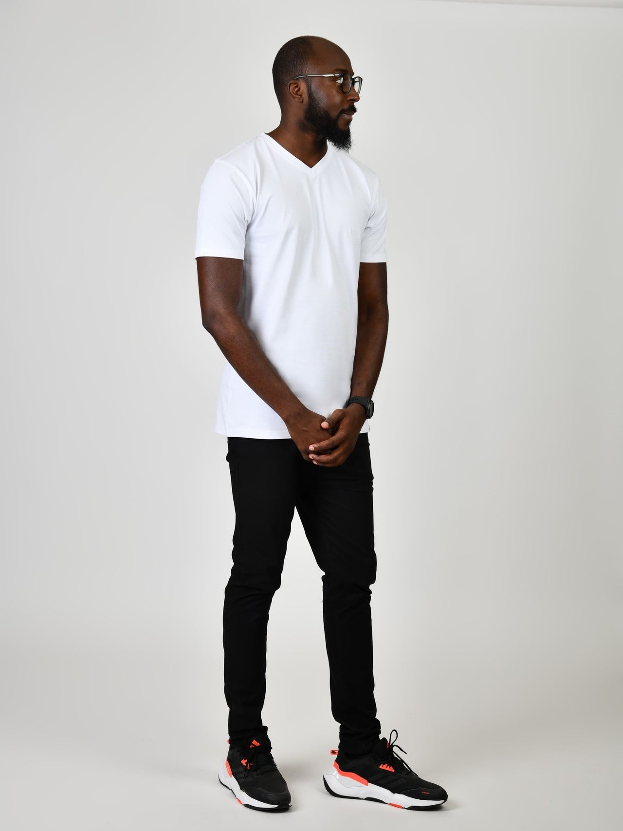 A head to toe shot of a tall and slim guy in the studio wearing a white L tall slim v-neck t-shirt.