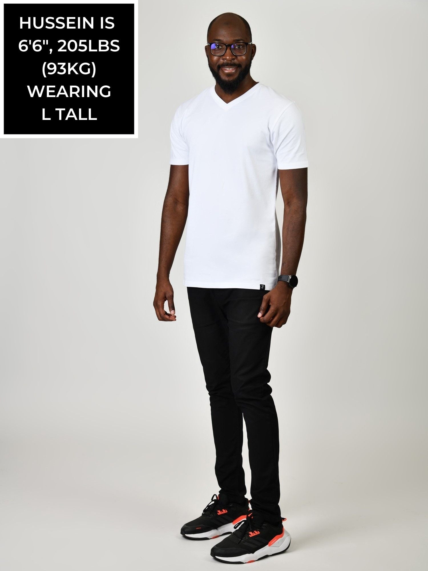 A head to toe shot of a tall and slim guy in the studio wearing a white L tall slim v-neck t-shirt.