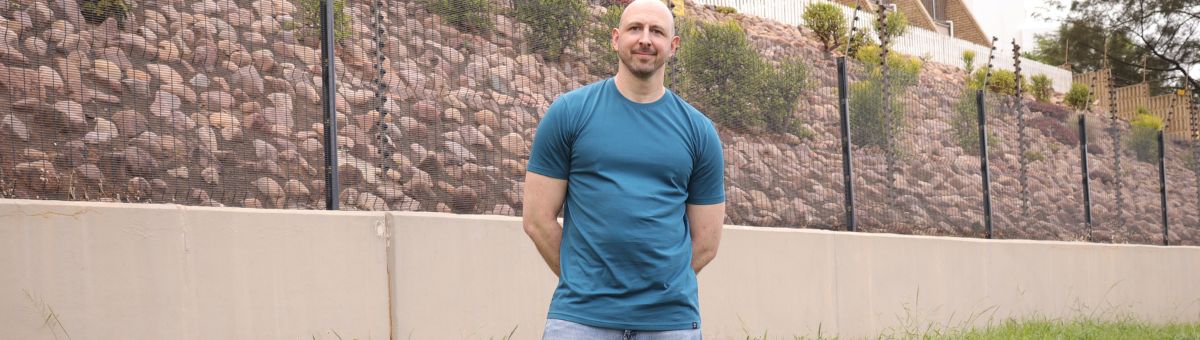 A tall slim guy wearing a petrol XL tall slim t-shirt.