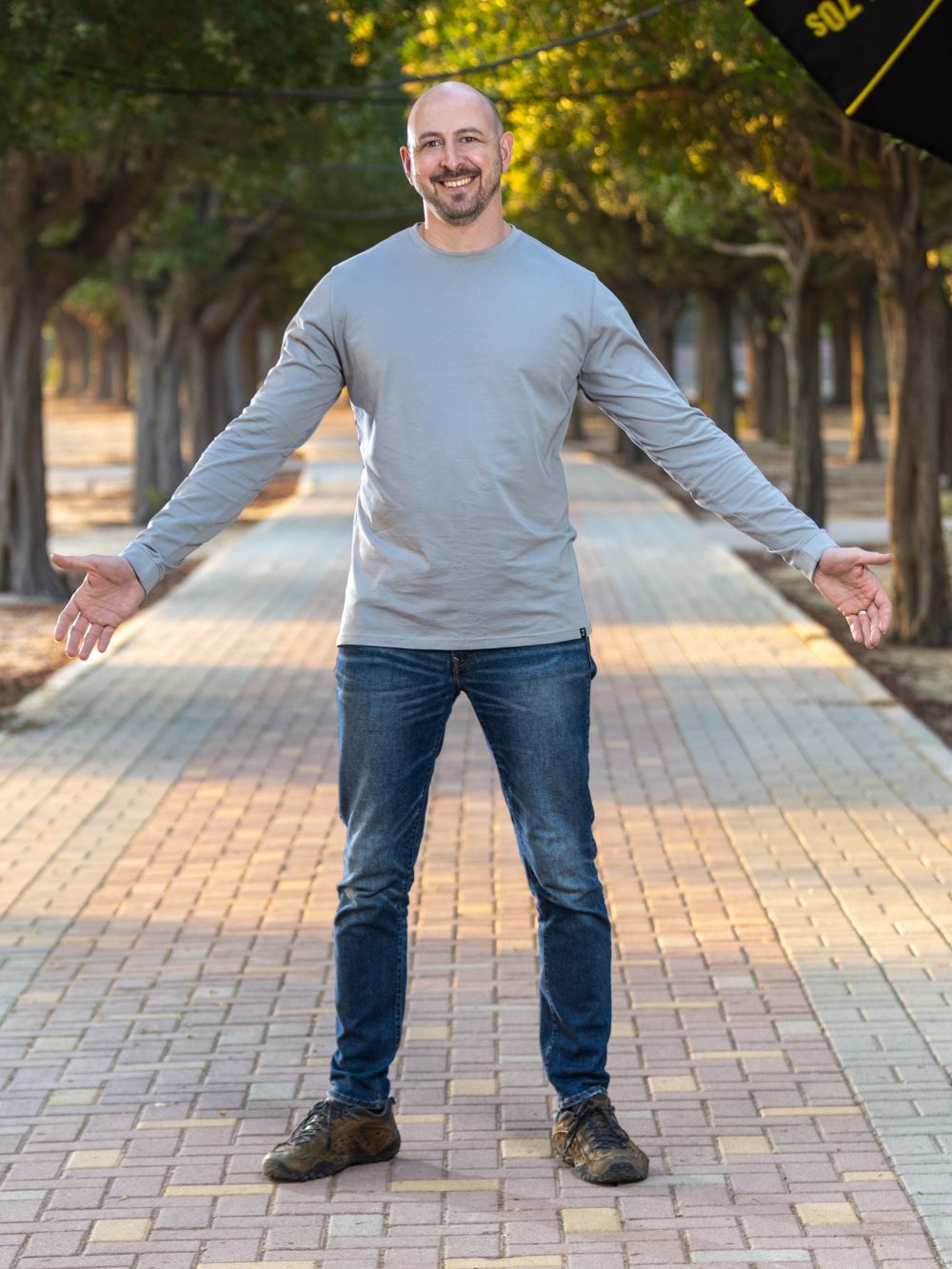 A tall athletic guy wearing an XL tall long sleeve grey t-shirt in a park.