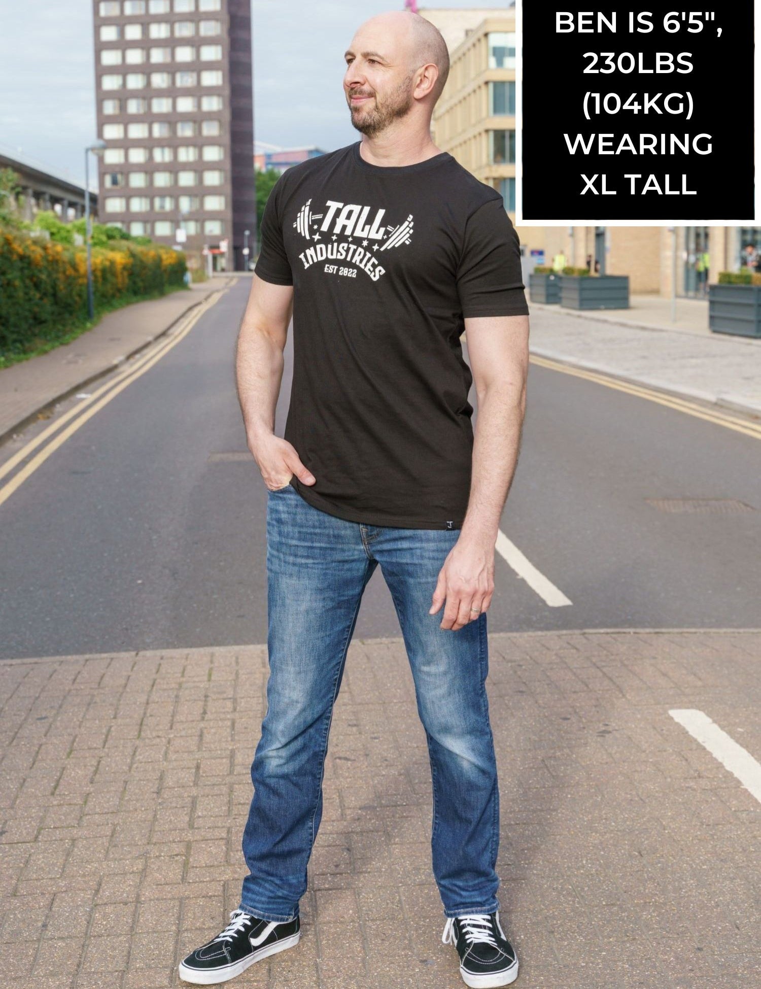 A head to toe shot of a tall skinny guy wearing a tall graphic bodybuilding t-shirt.