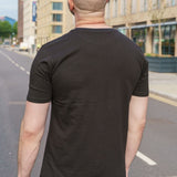 A shot from behind of a tall skinny guy wearing a tall slim graphic t-shirt.