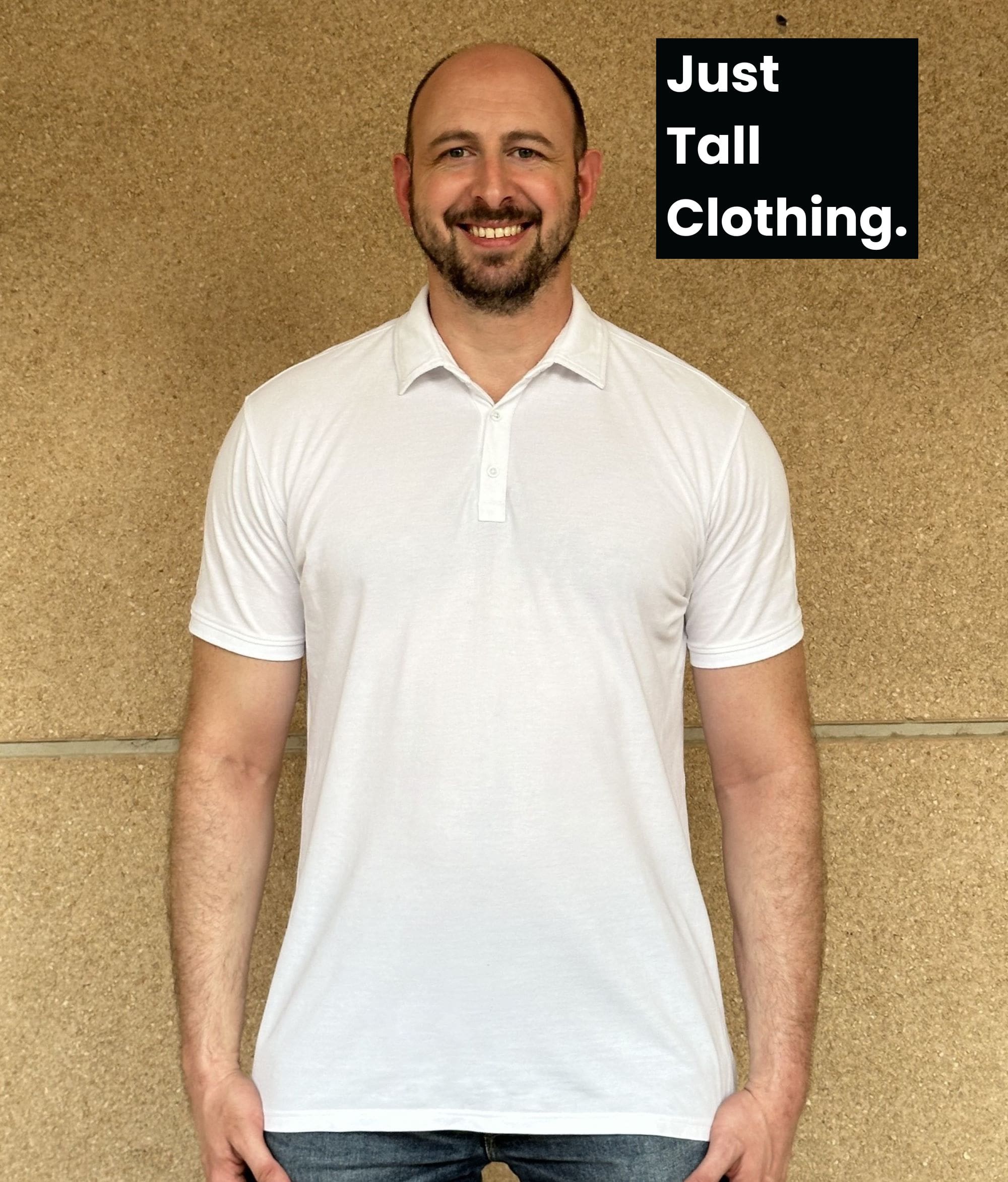 A tall slim guy who's smiling and happy as he's wearing a great fitting tall polo that's slim fitted and falling to below the belt line.