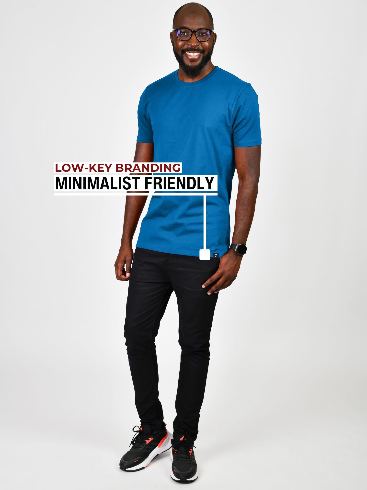 A head to toe shot of a tall slim guy in a studio wearing an azure large tall slim t-shirt and smiling.