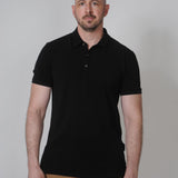 A tall slim guy in a studip and wearing a black XL tall polo shirt.