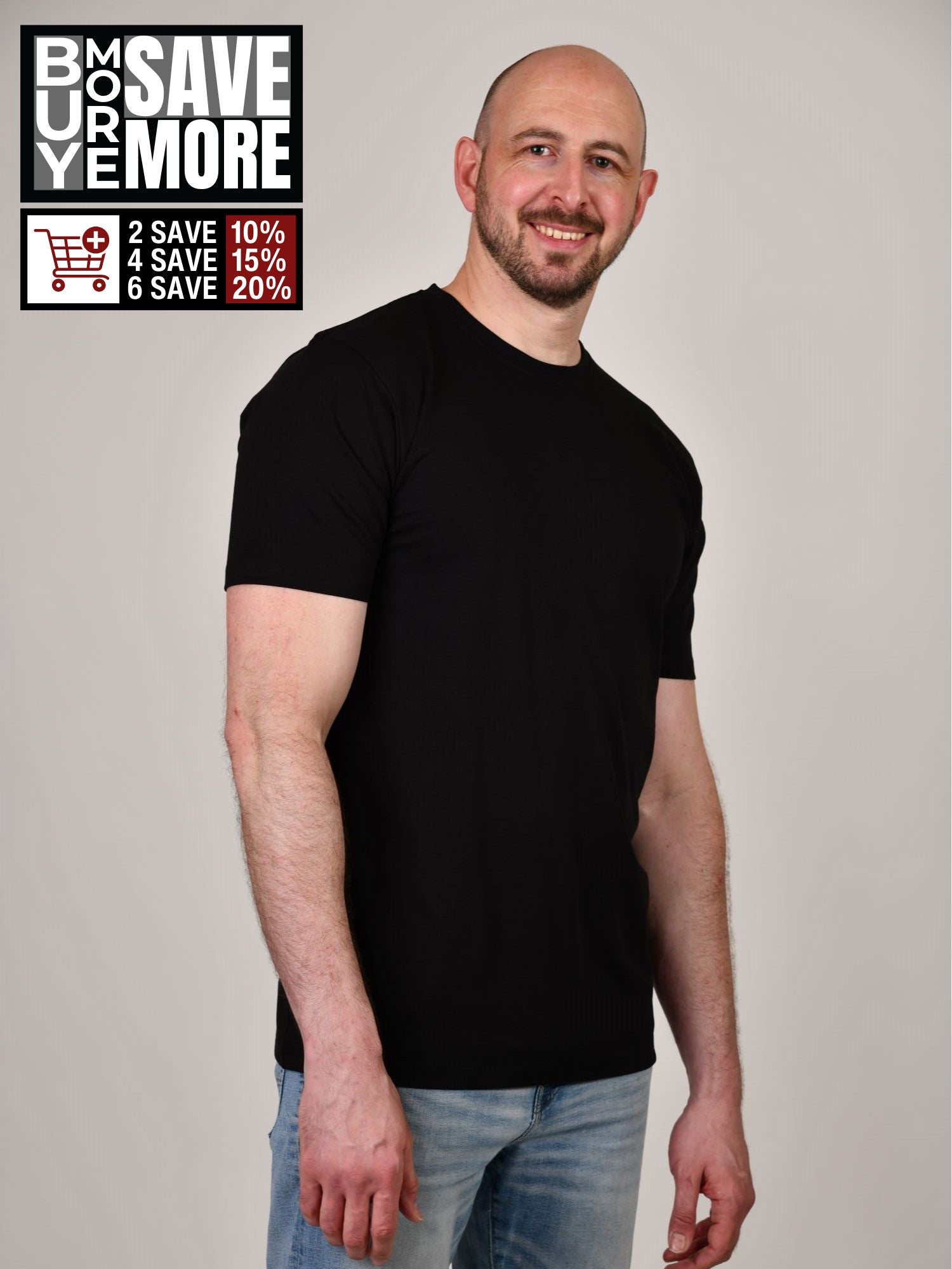 A tall and slim man in the studio standing in front of a light background. The smiling model is wearing an extra long slim black t-shirt in a size XL. The tall black t-shirt features a 3" longer body, 100% organic cotton, and is soft & preshrunk. The black t-shirt is ideal for tall slim men 6'2"+. Buy 2 Save 10%, Buy 4 Save 15%, Buy 6 Save 20%.