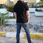 A shot from behind of a tall slim man wearing an XL tall black zip polo shirt.