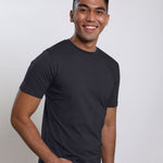 A tall and slim guy in the studio, hand in pocket and wearing a charcoal medium tall slim fit t-shirt.