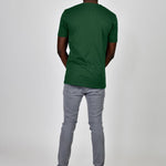 A shot from behind of a tall and slim guy in the studio and wearing a dark green L tall slim t-shirt.