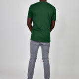 A shot from behind of a tall and slim guy in the studio and wearing a dark green L tall slim t-shirt.