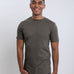 A tall and slim man in the studio standing in front of a light background. The smiling model is wearing an extra long slim dark grey t-shirt in a size medium. The tall dark grey t-shirt features a 3" longer body, 100% organic cotton, and is soft & preshrunk. The dark grey t-shirt is ideal for tall slim men 6'2"+.