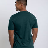 A shot from behind of a tall slim guy wearing a dark teal medium tall t-shirt.