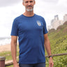 A tall and slim man standing by the sea. The smiling model is wearing a navy blue extra long graphic t-shirt with a minimal lake design. It features a 3" longer body, 100% organic cotton, and is soft & preshrunk. This extra long tall graphic tee is ideal for tall slim men 6'2"+