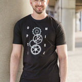 A tall and slim man standing outside under a bridge. The smiling model is wearing a black extra long graphic t-shirt with the text optimise and cogs in the middle. It features a 3" longer body, 100% organic cotton, and is soft & preshrunk. This extra long tall graphic tee is ideal for tall slim men 6'2"+.
