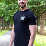 An upper body shot of a tall slim guy in a park wearing an XL tall and slim fitting graphic t-shirt in black.