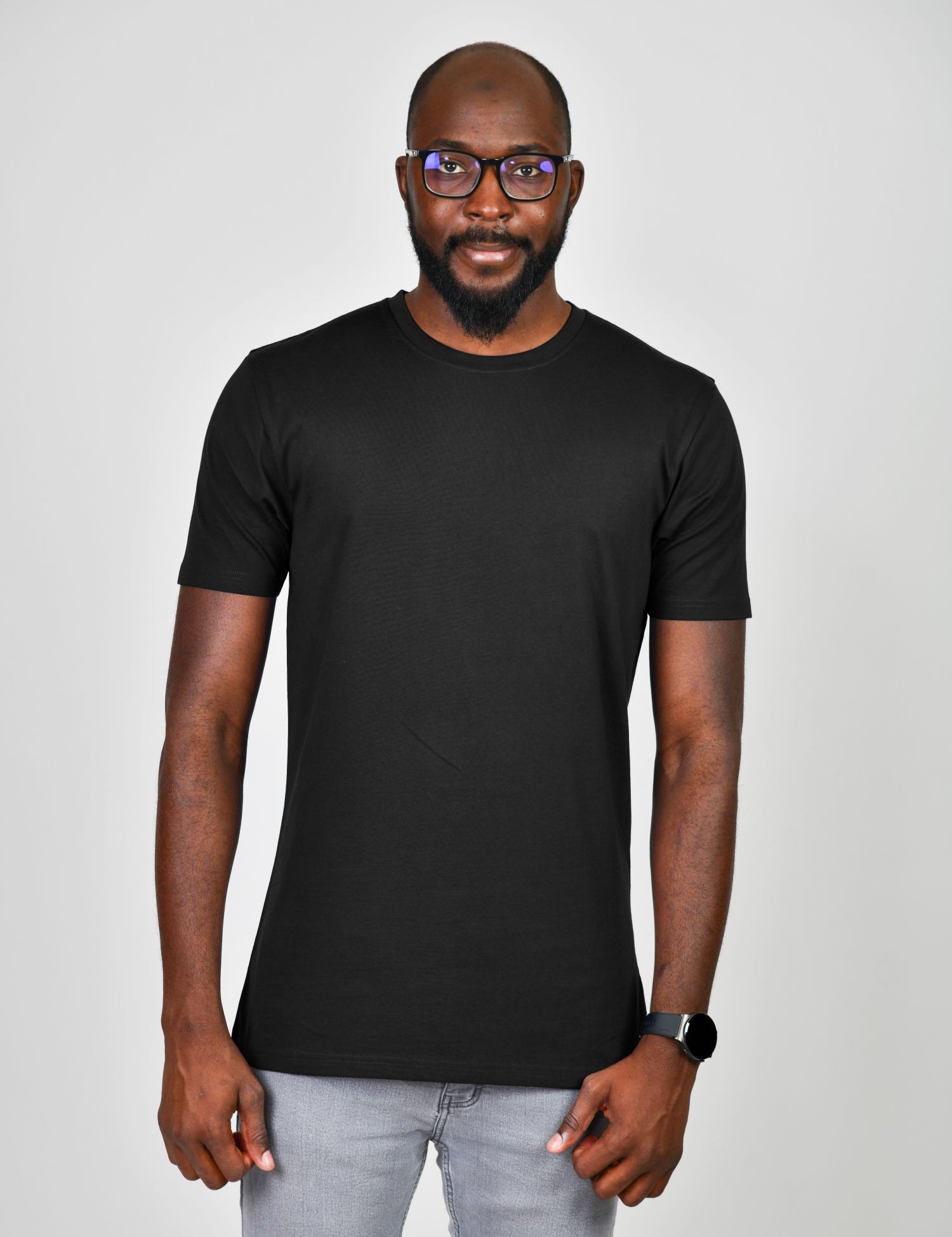 A tall slim guy wearing a large tall heavyweight black t-shirt, hands at his sides and smiling.