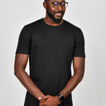 An upper body shot of a tall slim guy wearing a large tall heavyweight black t-shirt, looking down and smiling.
