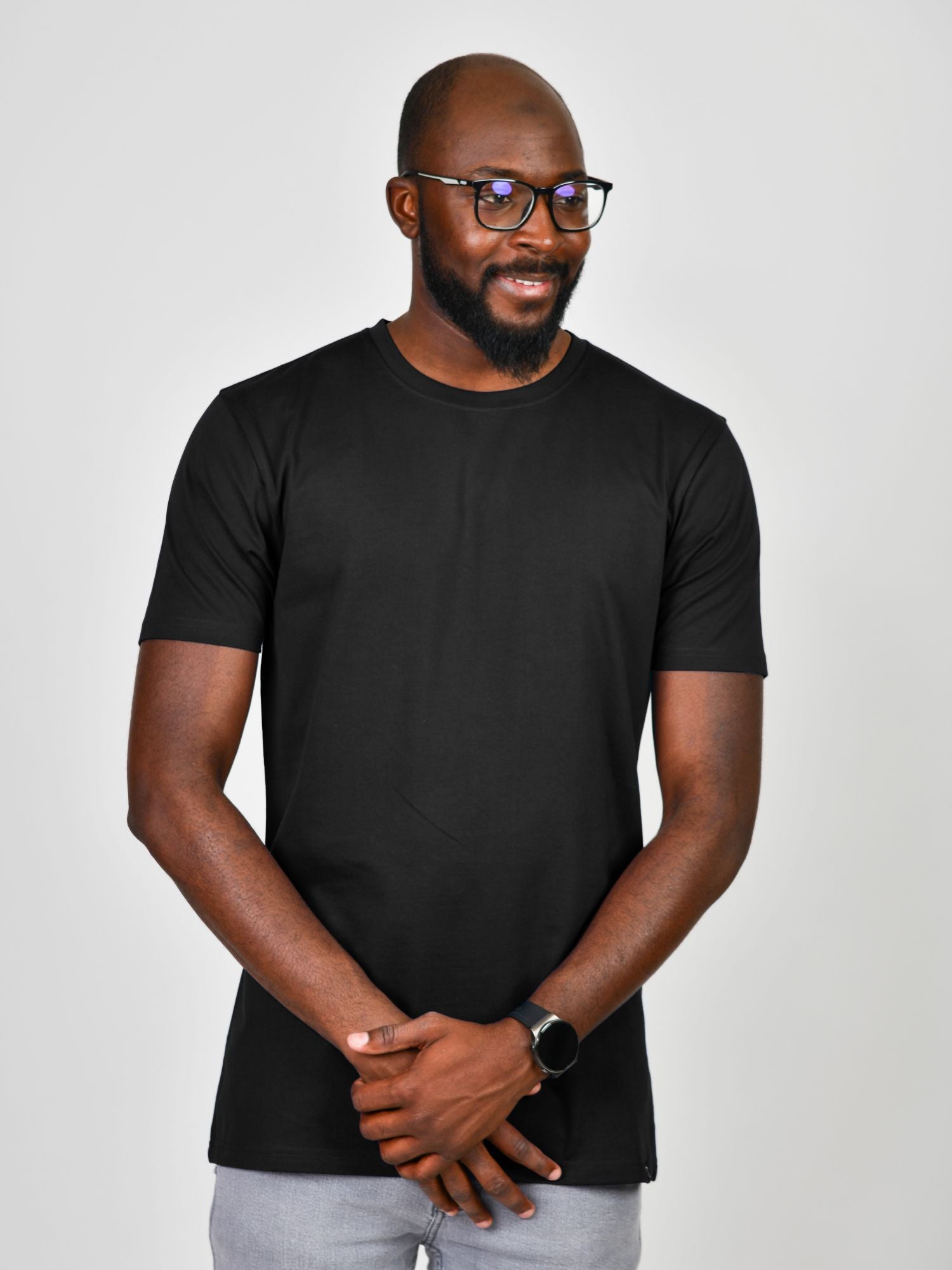 An upper body shot of a tall slim guy wearing a large tall heavyweight black t-shirt, looking down and smiling.
