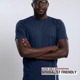 A tall slim man wearing a large tall heavyweight midnight blue t-shirt, arms folded.