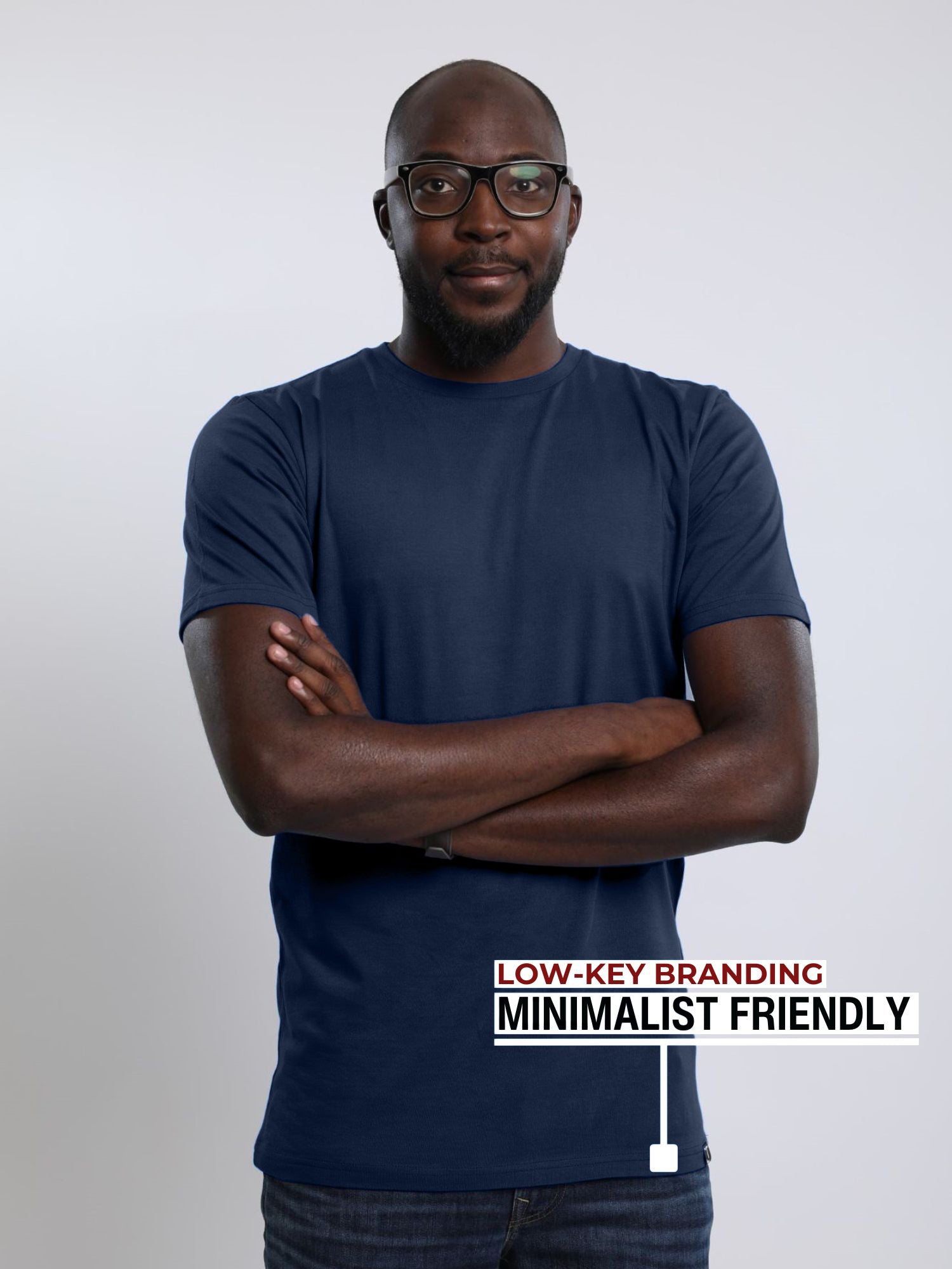 A tall slim man wearing a large tall heavyweight midnight blue t-shirt, arms folded.