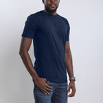 An upper body shot of a tall slim guy wearing a large tall midnight blue t-shirt, one hand in pocket.