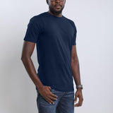 An upper body shot of a tall slim guy wearing a large tall midnight blue t-shirt, one hand in pocket.