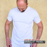 A tall slim man wearing an XL tall heavyweight white t-shirt and looking down at the Just Tall hem logo.