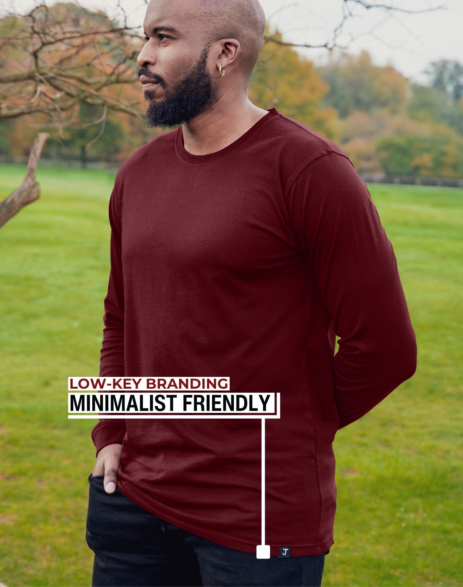An upper body shot of a tall athletic guy wearing an XL tall maroon long sleeve t-shirt, standing in a park and looking to the right side.