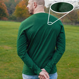 A shot from behind of a tall slim guy in a park wearing an extra long sleeve long sleeve tall t-shirt in green.