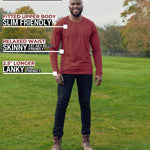 A head to toe shot of a tall athletic guy in a park wearing a dark orange long sleeve tall t-shirt.