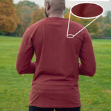 A shot from behind of a tall slim guy in a park wearing an extra long sleeve long sleeve tall t-shirt in dark orange.