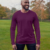 A tall athletic guy wearing a long sleeve dark purple tall t-shirt and smiling in a park while looking to the left.