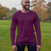 A tall athletic guy wearing a long sleeve dark purple tall t-shirt and smiling in a park while looking to the left.