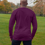 A shot from behind of a tall athletic guy wearing a long sleeve dark purple tall t-shirt.