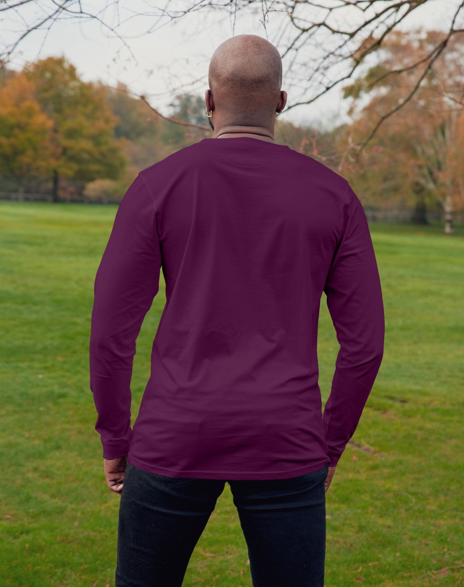 A shot from behind of a tall athletic guy wearing a long sleeve dark purple tall t-shirt.