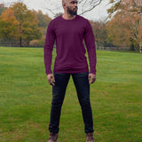 A head to toe shot of a tall lean guy in a  park, wearing a dark purple tall long sleeve t-shirt and looking to the left.