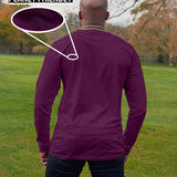 A shot from behind of a tall slim guy in a park wearing an extra long sleeve long sleeve tall t-shirt in dark purple.